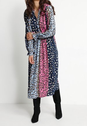 Abito con stampa leopardata caratterizzato da sezioni alternate in blu navy, azzurro, beige e rosa. Maniche lunghe e abbinato a stivali neri con tacco.