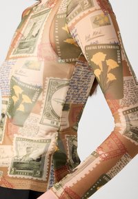 Long-sleeve top made of semi-transparent material, featuring a collage of vintage postage stamps and handwritten notes in earthy colors.