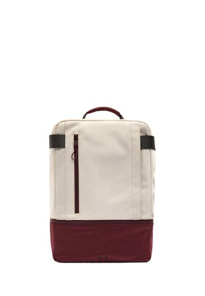 Prostokątny plecak w dwóch kolorach z beżową górą i bordowym dołem, pionowa kieszeń na zamek, czarne uchwyty oraz górny uchwyt do noszenia.