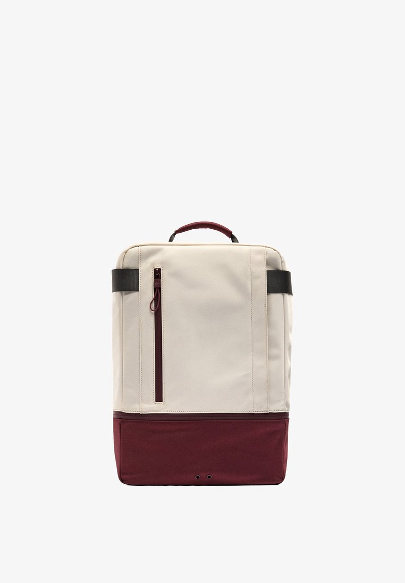 Prostokątny plecak w dwóch kolorach z beżową górą i bordowym dołem, pionowa kieszeń na zamek, czarne uchwyty oraz górny uchwyt do noszenia.