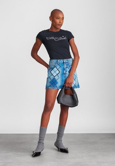 Μαύρη εφαρμοστή μπλούζα με λογότυπο "Marc Jacobs", μπλε τζιν μίνι φούστα με διαμαντένιο σχέδιο, γκρίζες κάλτσες μέχρι το γόνατο, μαύρη τσάντα χειρός και ψηλοτάκουνα παπούτσια.