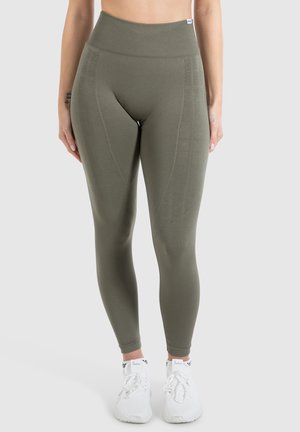 Olivengrønne højtaljede leggings med en ribbet talje og strukturerede paneler. Bæres med hvide sportsko. Glat, strækbart stof.
