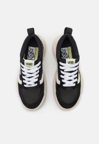Svarte og hvite Vans sneakers med tekstiloverdel, lagdelt design og gummisåle. Egenskaper inkluderer hvite snørebånd og logo på tungen.