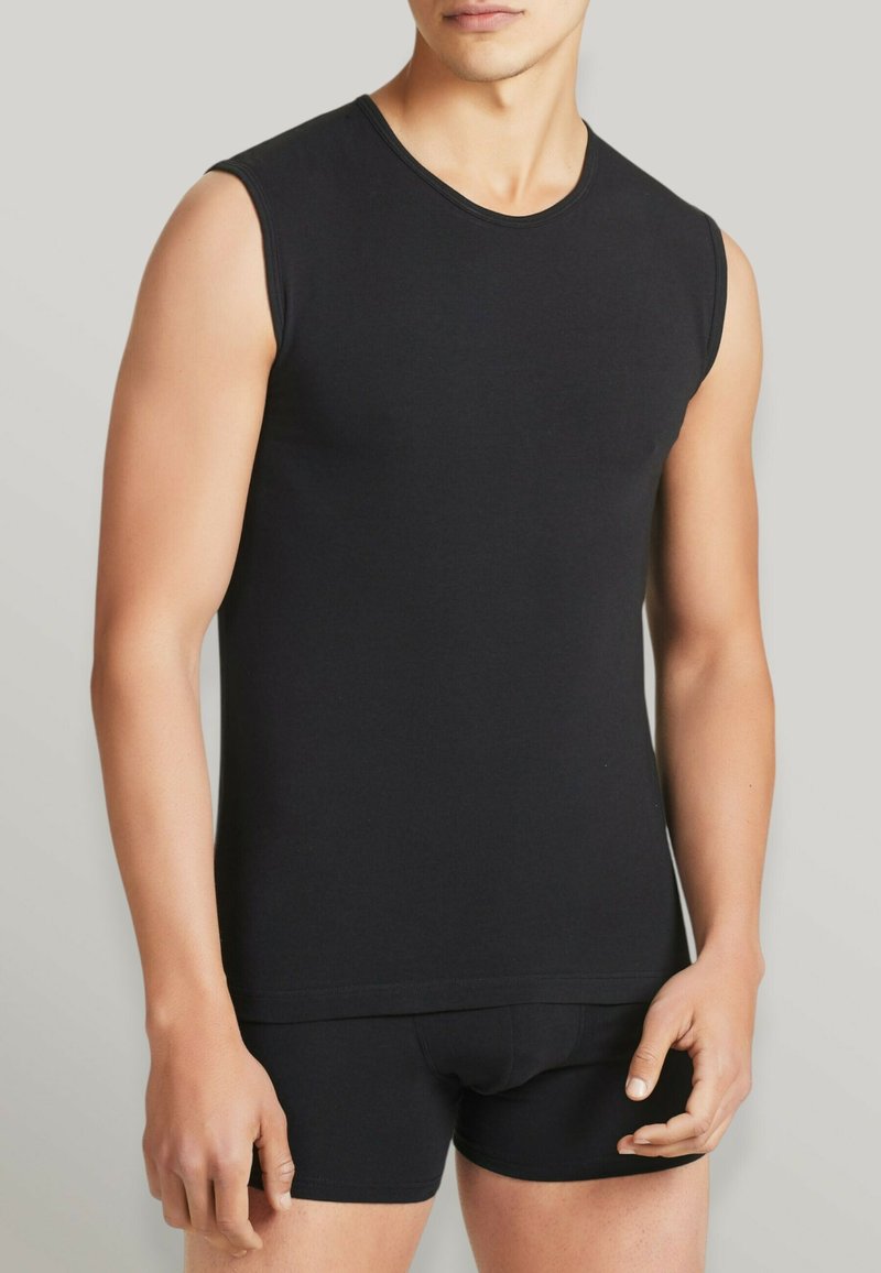Camisetta nera senza maniche in morbido jersey di cotone, con scollatura rotonda e design aderente, abbinata a biancheria intima nera.