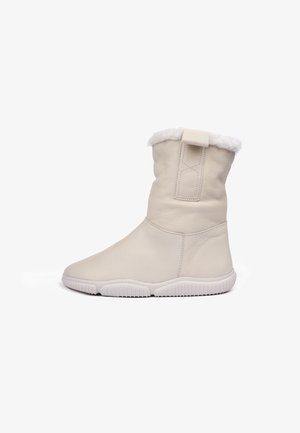 Bota de tobillo de cuero blanco con un puño de pelaje, puntera redonda, suela de goma texturizada y una lengüeta en la parte posterior. Superficie lisa y diseño minimalista.