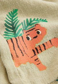 Ilustracja pomarańczowego tygrysa z czarnymi paskami i zielonymi liśćmi palmowymi na beżowej tkaninie o fakturze.