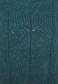 Pull en tricot teal avec un motif texturé comprenant des lignes entrelacées en relief et un léger brillant, fabriqué à partir d'un fil duveteux.