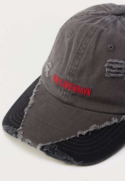 Szürke, kopott baseballsapka rojtos szegélyekkel, hímzett piros "HAN KJØBENHAVN" felirattal és texturált fekete alsó résszel.