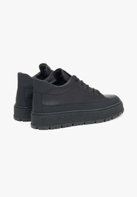 Czarne skórzane sneakersy z teksturowaną gumową podeszwą, okrągłym noskiem i sznurowanym zapięciem. Subtelne detale szwów wzdłuż boków.