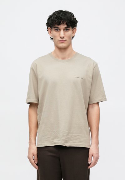 Μπεζ βαμβακερό T-shirt με κοντά μανίκια και στρογγυλή λαιμόκοψη. Διαθέτει ένα μικρό λογότυπο "Tiger of Sweden" στο αριστερό στήθος. Κανονική εφαρμογή.