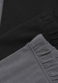 Tre tygbitar i svart, mörkgrått och ljusgrått. Mjuk bomullsduk med subtil textur och fransade kanter på den svarta biten.