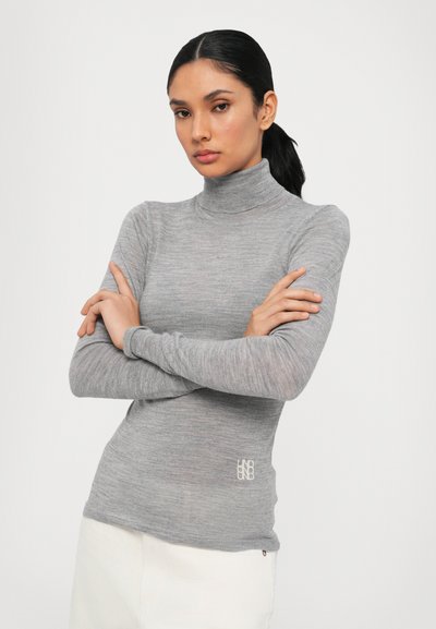 Gray turtleneck top made from a soft, textured fabric. Long sleeves and fitted design with a small logo on the lower side.