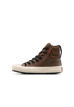 Baskets montantes marron en cuir avec des lacets noirs, un embout en caoutchouc crème et une semelle noire texturée. Présente un accent de logo rouge.