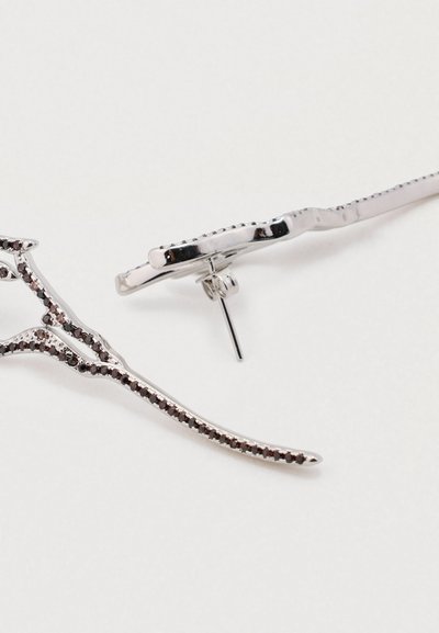 Brincos em tom prateado com um design de ramo alongado, apresentando acentos de pedras preciosas pretas ao longo da borda e um fecho de pressão seguro.