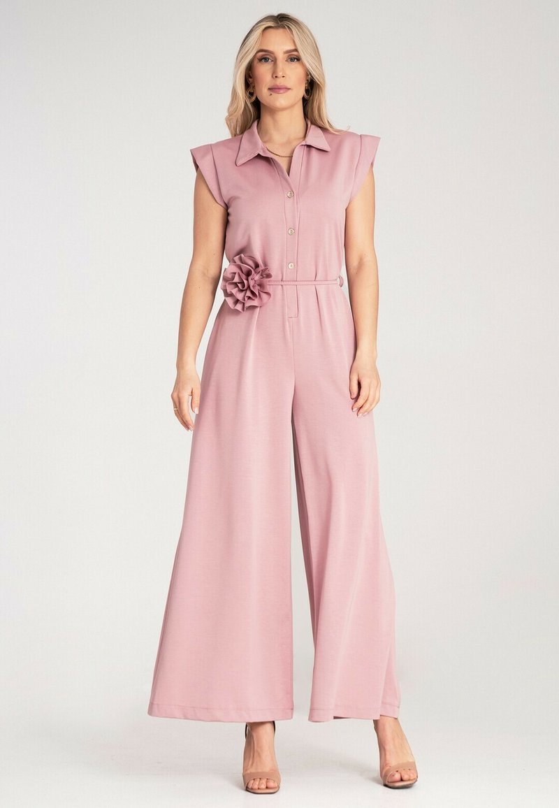 Różowy bezrękawnik z kołnierzykiem, zapinany na guziki z szerokimi nogawkami i kwiatowym akcentem w talii, wykonany z miękkiego materiału.