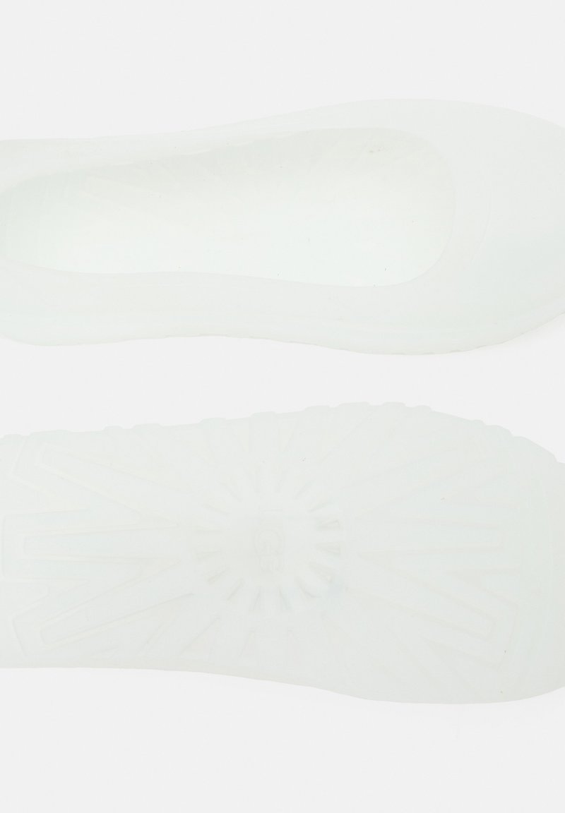 Białe wsuwane buty o gładkiej, błyszczącej powierzchni. Zaokrąglony czubek, elastyczny materiał i fakturowana podeszwa z promienistymi wzorami.