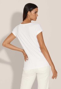 Witte T-shirt met korte mouwen en een ronde hals, gemaakt van zachte stof en met een relaxte pasvorm, gecombineerd met lichte broek.