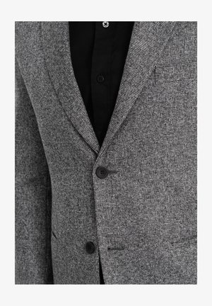 Grijs geruit blazer van textuurstof, met een notch lapel, twee knopen en een borstzak, gestyled met een zwart shirt eronder.