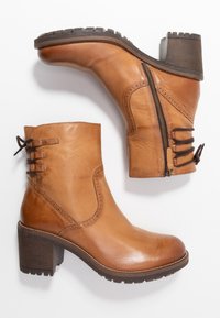 Hnědé kožené kotníkové boty s blokovým podpatkem, bočním zipem a dekorativním šněrováním. Hladký povrch s jemnými švovými detaily.