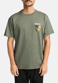 Olijfgroene katoenen t-shirt met korte mouwen, een ronde hals en een meerkleurige graphic print op de borst met abstracte vormen.