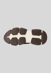 Suola di scarpa sportiva in bianco e nero, caratterizzata da un motivo di grip testurizzato, sezioni lisce e un design con punta arrotondata.