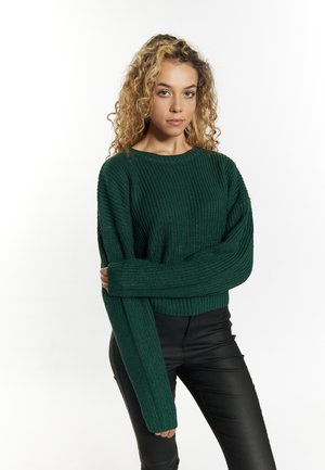 Groen gebreid sweater met een geribbelde textuur, ronde halslijn en lange mouwen. Gekocht met zwarte slim-fit broek.