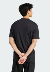 Czarny t-shirt z okrągłym dekoltem, wykonany z bawełny, z krótkimi rękawami, widocznymi szwami i luźnym krojem. Gładka tekstura, bez wzorów czy akcentów.