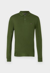 Zelená dlhá polo košeľa s dlhým rukávom vyrobená z bavlny s trojitou gombíkovou légiou a malým logom na ľavom prse. Hladká textúra.