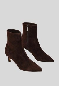 Stivali alla caviglia in suede marrone con punta appuntita e tacco piccolo. Presentano una cerniera laterale e una texture liscia.