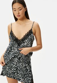 Sort og hvid leopardmønstret camisole med blondekant, der har tynde justerbare stropper og en afslappet pasform, der falder blødt.