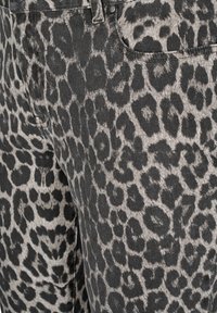 Tejido de mezclilla con estampado de leopardo en gris y negro, con manchas distintivas, peso medio y una textura suave. Incluye bolsillos y detalles de costura.
