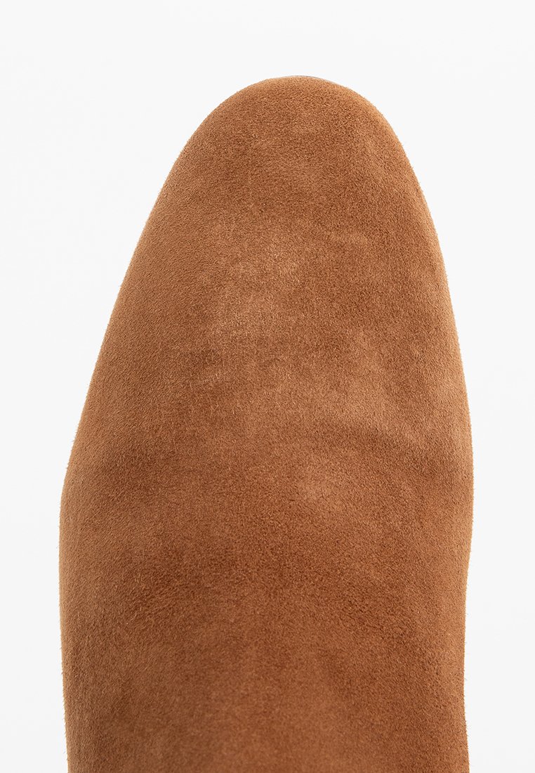 Bottine en suède marron avec un bout rond, une texture lisse et une silhouette élégante. Pas de quincaillerie ni de motifs visibles.