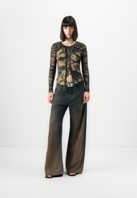 Langärmliges, eng anliegendes Oberteil mit einem floralen Muster in dunklen Farben; kombiniert mit weit geschnittenen, verwaschenen schwarzen Jeans.