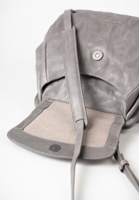 Borsa in pelle grigia con una trama morbida, dotata di un flap frontale, una chiusura a scatto e una tracolla removibile. Fodera interna in suede dello stesso colore.