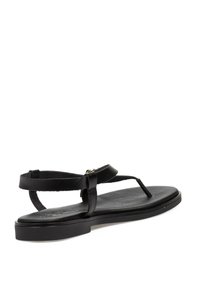 Sanda de cuero negra con tiras finas, suela plana y un diseño minimalista. Presenta un separador para el dedo y una correa de tobillo ajustable para un mejor ajuste.