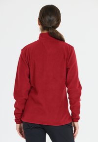 Röd fleecejacka med hög krage och långa ärmar, med en mjuk textur och rak passform, lämplig för utomhusbruk.