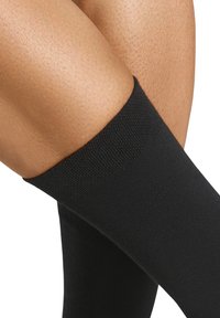 Black knee-high socks with a smooth texture, featuring a ribbed cuff and seamless design, contrasting with light skin tones.