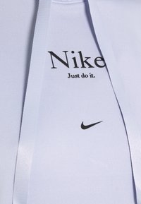 Ljusblå träningsoberkläder med en figursydd design. Svart "Nike"-logotyp och texten "Just do it." tryckt på framsidan. Slät, elastisk tyg.