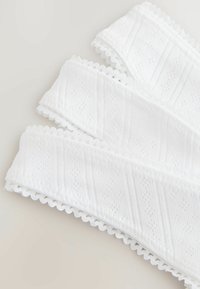 Tessuto con bordo in pizzo bianco che presenta un motivo a rombi testurizzato con bordi smerlati. Tre strisce sovrapposte su uno sfondo neutro.