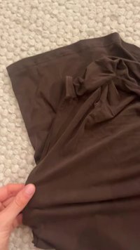 Brown, soft fabric draped and creased, showcasing a smooth texture and a flowing design with subtle light reflections.