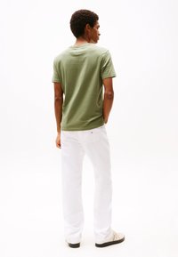 Tricou verde din bumbac cu guler rotund, asociat cu blugi albi drepți. Tricoul are mâneci scurte, în timp ce blugii dispun de buzunare standard la spate.