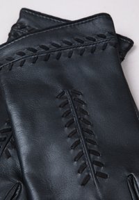 Black leather gloves with textured stitching and a smooth finish. Features prominent decorative seams along the back for added detail.