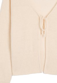 Kremowy sweter robiony na drutach z dekoltem w serek, z zapięciem na sznurki i prążkowanym dołem. Tekstura jest miękka i lekko puszysta, co zapewnia lekki komfort noszenia.