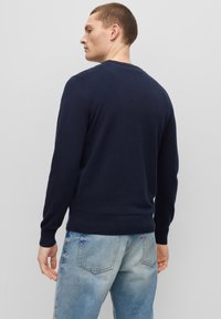 Navyblauwe gebreide trui met een ronde hals, geribbelde manchetten en zoom. Draag het met lichtblauwe verwasemden jeans. Zachte textuur, casual pasvorm.