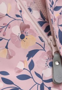 Tessuto floreale zipato di un delicato rosa, con fiori gialli e viola e foglie verdi; texture liscia e zip in metallo come dettaglio.