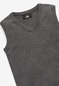 Pull sans manches gris avec un col en V, fabriqué en tissu texturé. Présente un col côtelé et des bords nets, marqué "next SCHOOL".