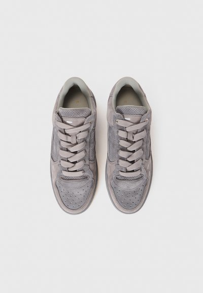 Un paio di sneaker grigie in suede con punte perforate e lacci abbinati, mostrate da una vista dall'alto su uno sfondo bianco.
