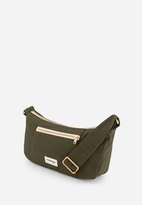 Sac en tissu vert foncé avec une texture lisse, doté d'une fermeture éclair dorée et d'une poche avant. Bretelle réglable et design minimaliste.