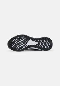 Suela exterior de goma negra con un patrón de agarre texturizado, que presenta una entresuela blanca y un diseño de punta redondeada para mayor comodidad y soporte.