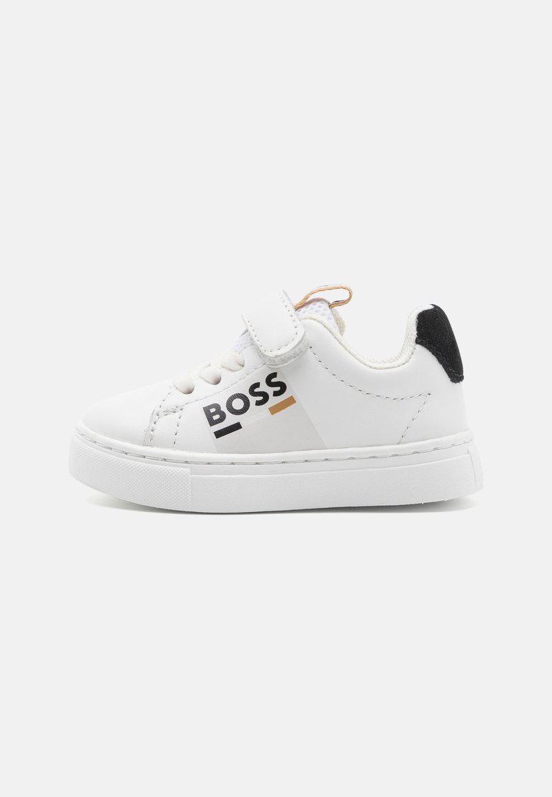 Witte sneaker met een glad leren bovenwerk, klittenbandsluiting, zwarte hakaccent en zwart-gouden "BOSS" logo op de zijkant.